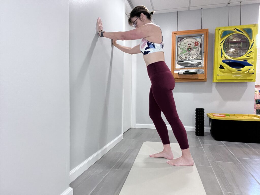 calf stretch facing wall while pressing down on back leg